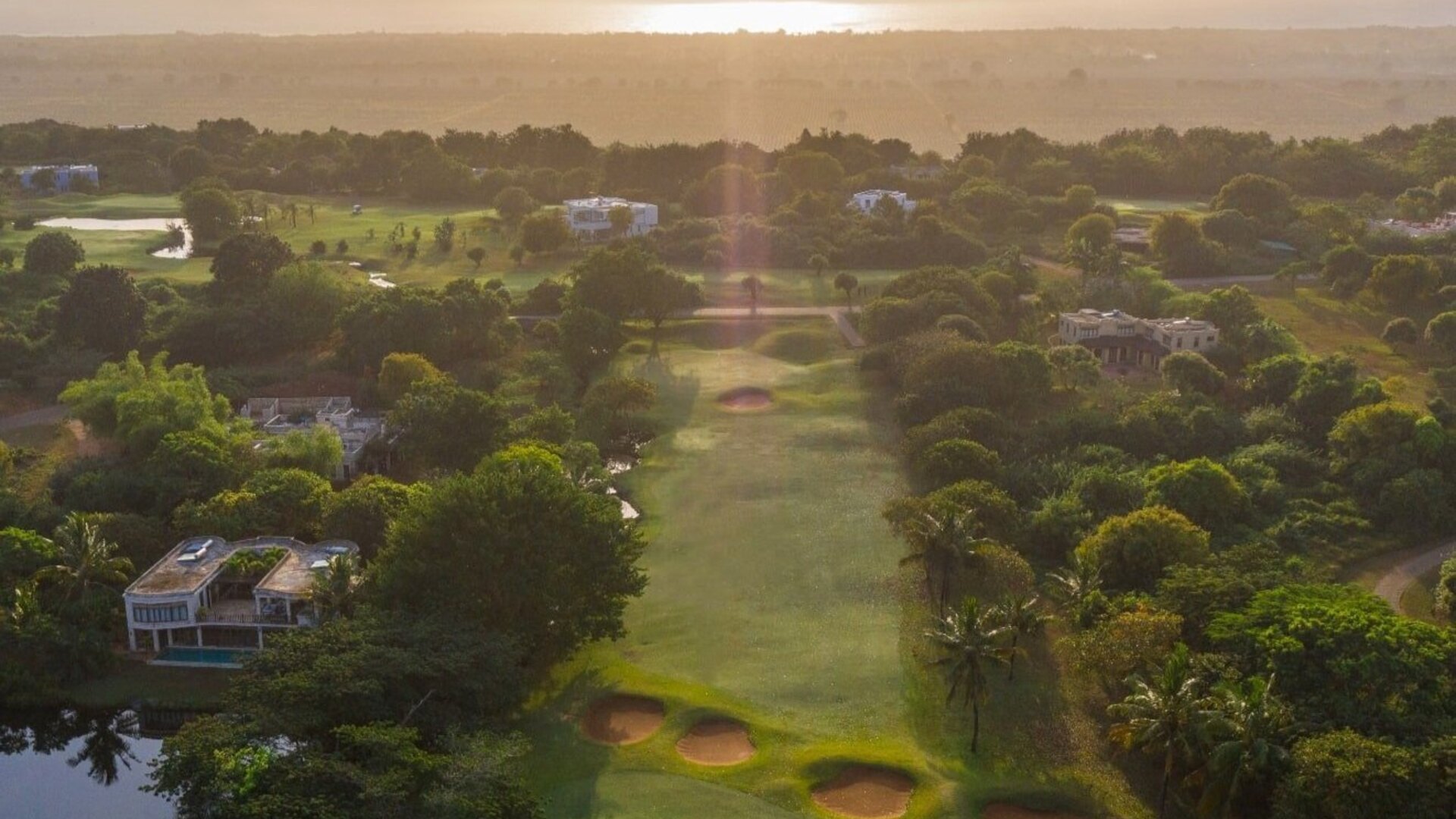 Golfers walking a fairway at Vipingo Ridge in Kenya as a giraffe browses beside the green