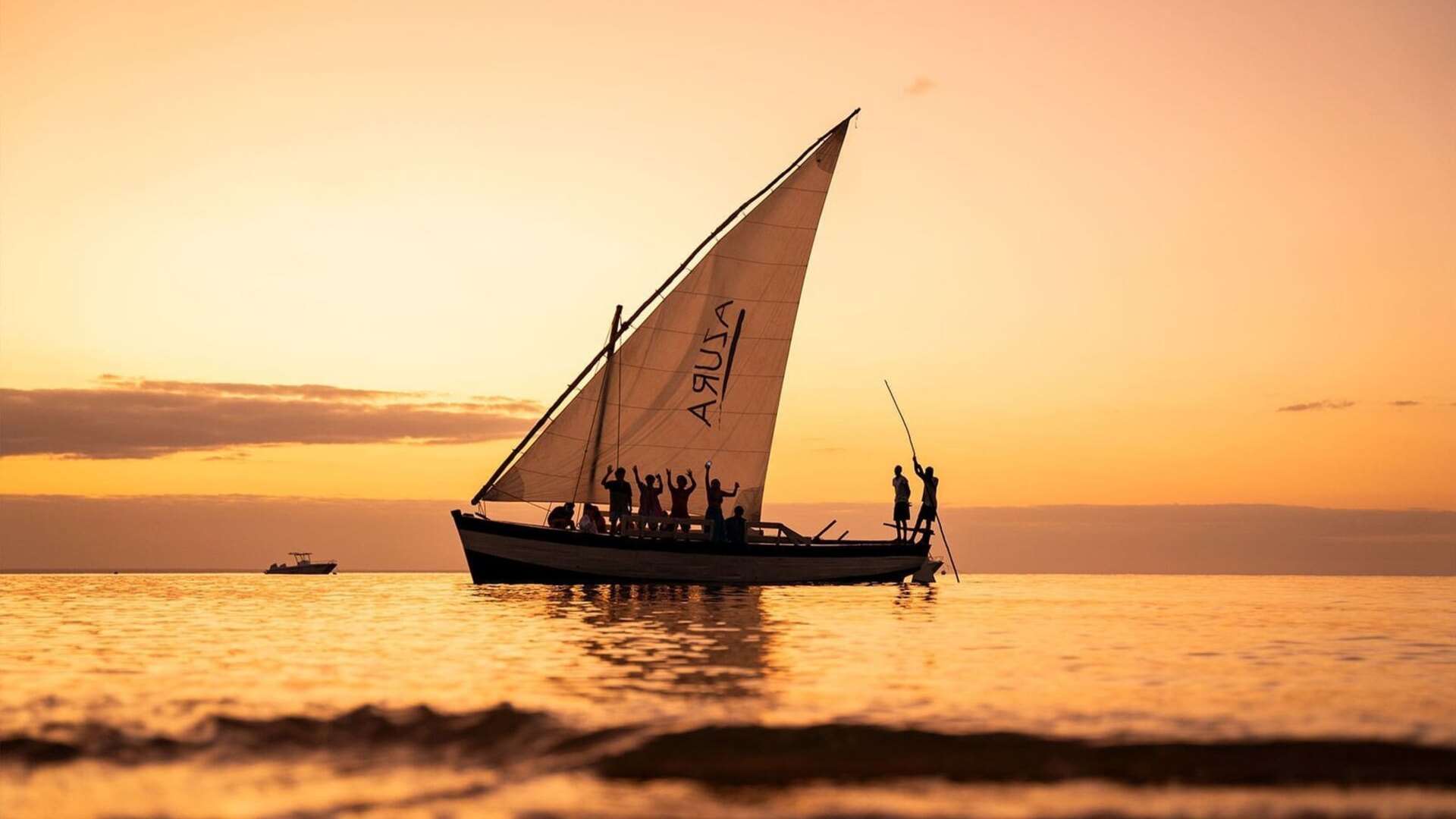 A traditional dhow sailing on molten-gold water at sunset off the Mozambique coast — a Kruger and Mozambique bush-and-beach honeymoon with Beyond Africa Safaris