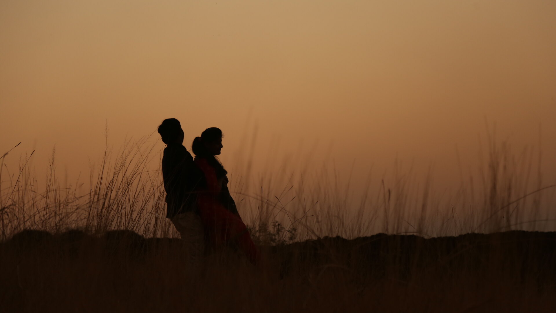 A couple silhouetted together against a golden African sunset