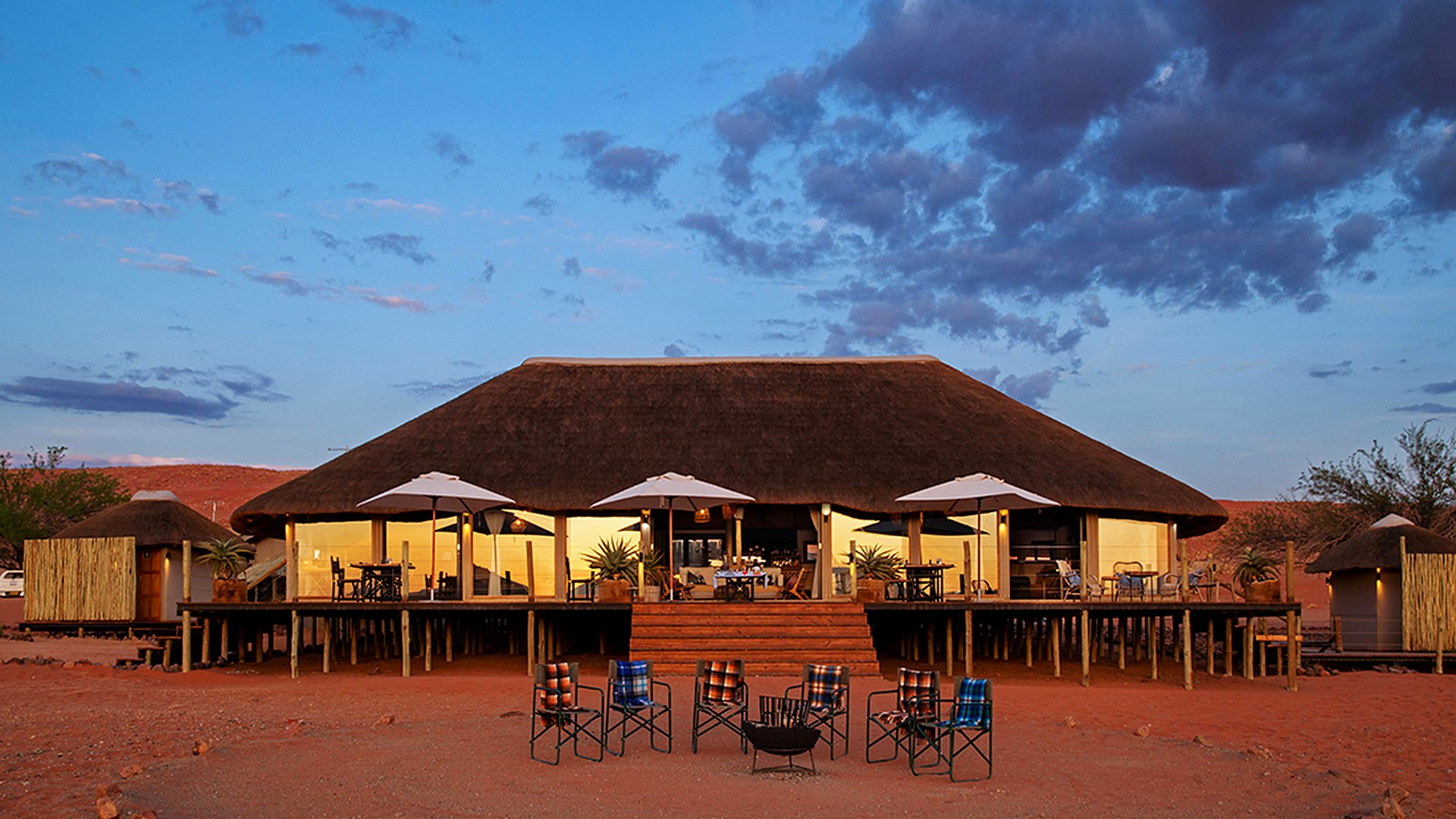 The lit main area of Kwessi Dunes glows at dusk over the plains of the NamibRand Nature Reserve