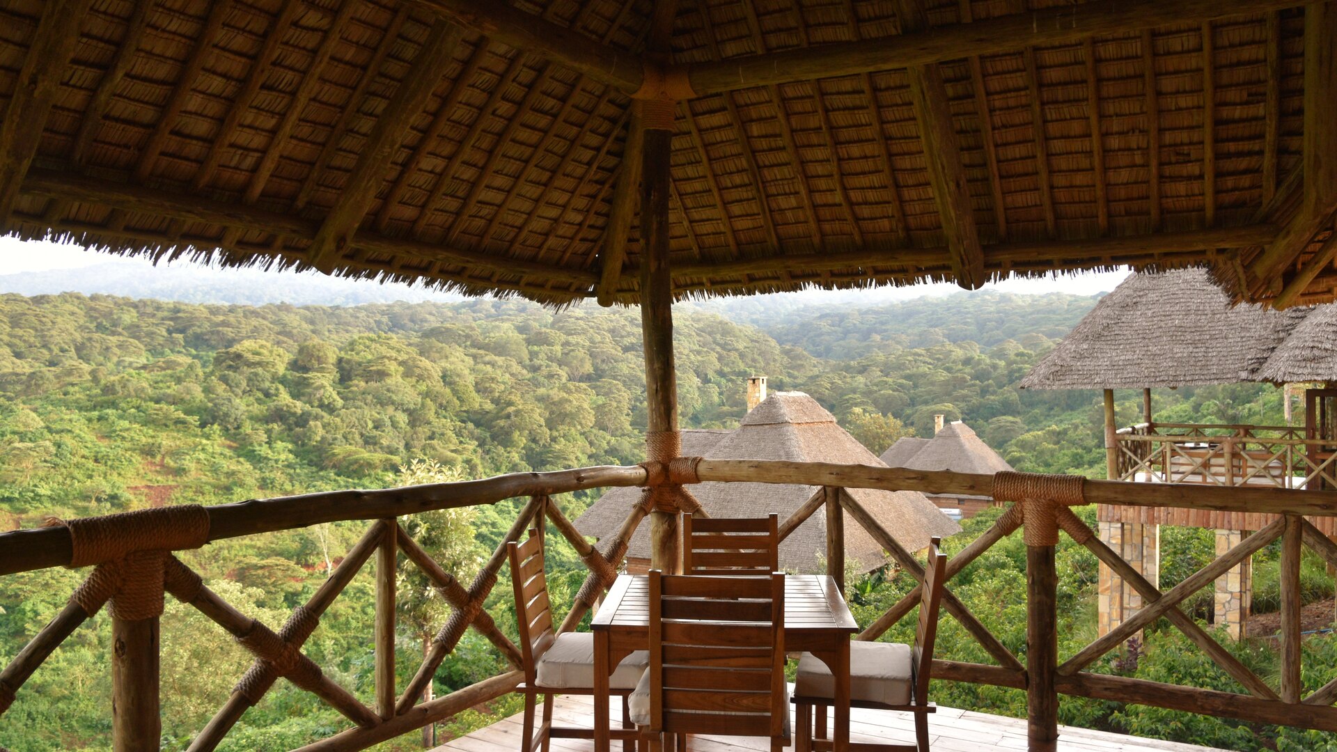 A thatched safari lodge deck overlooking a wide valley, set for the whole family