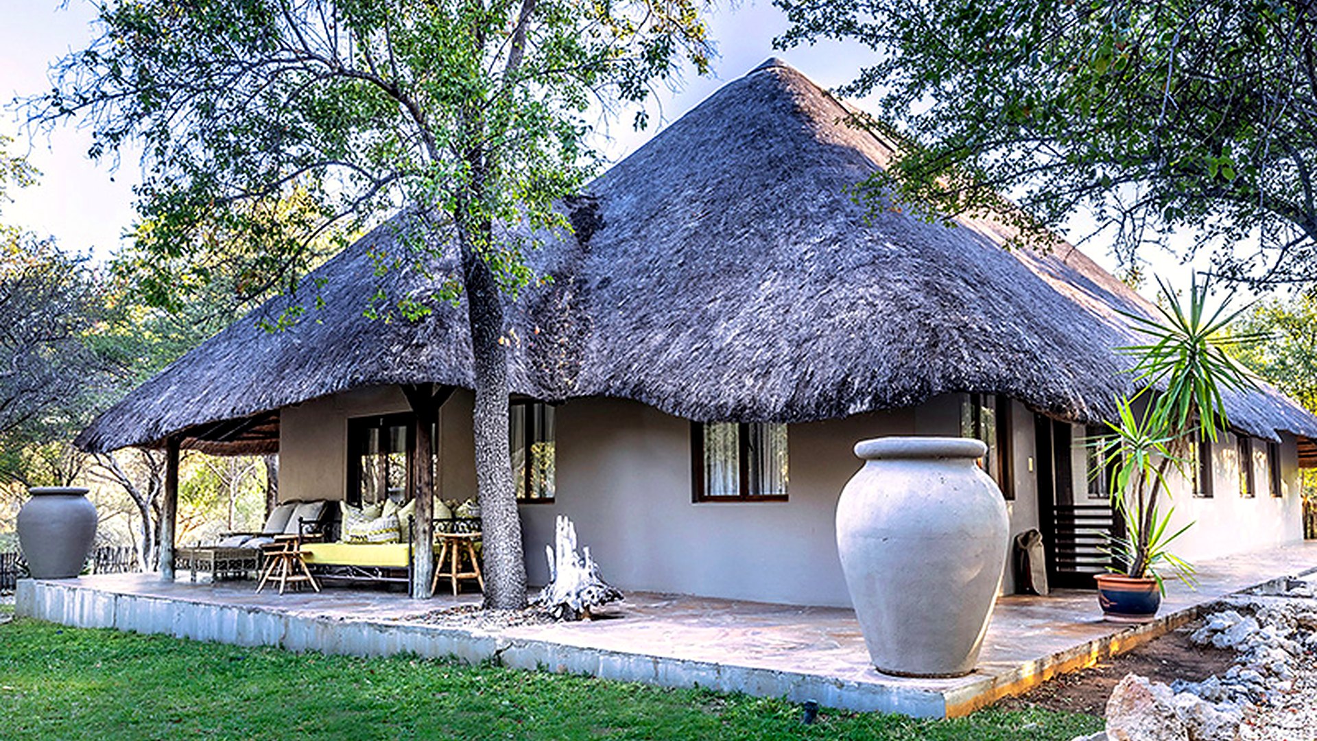 Thatched chalets of Mushara Lodge set among the mopane woodland near Etosha National Park