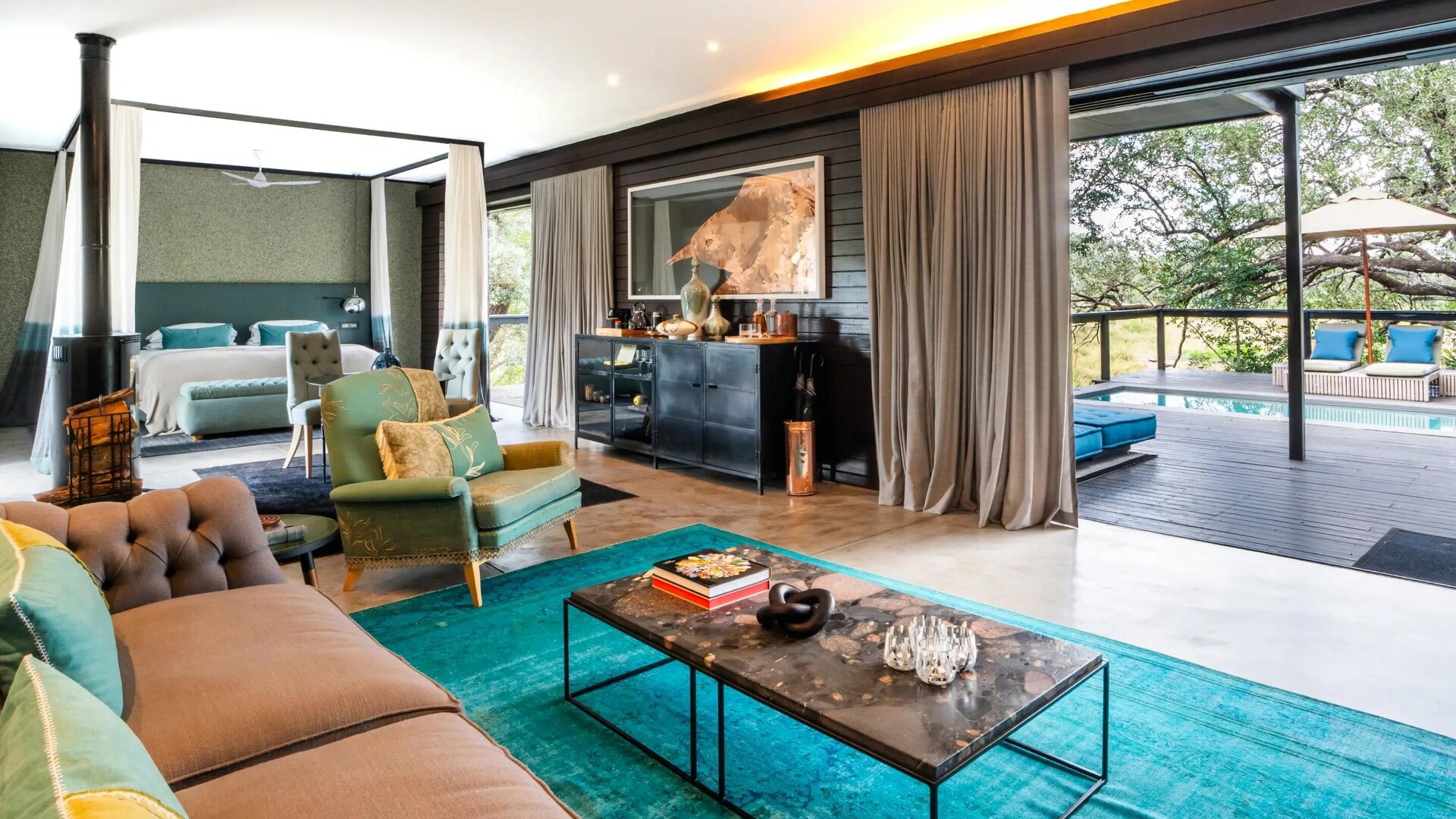 A design-led Silvan Safari suite opening through glass onto a private deck and the Manyeleti River bush in the Sabi Sand