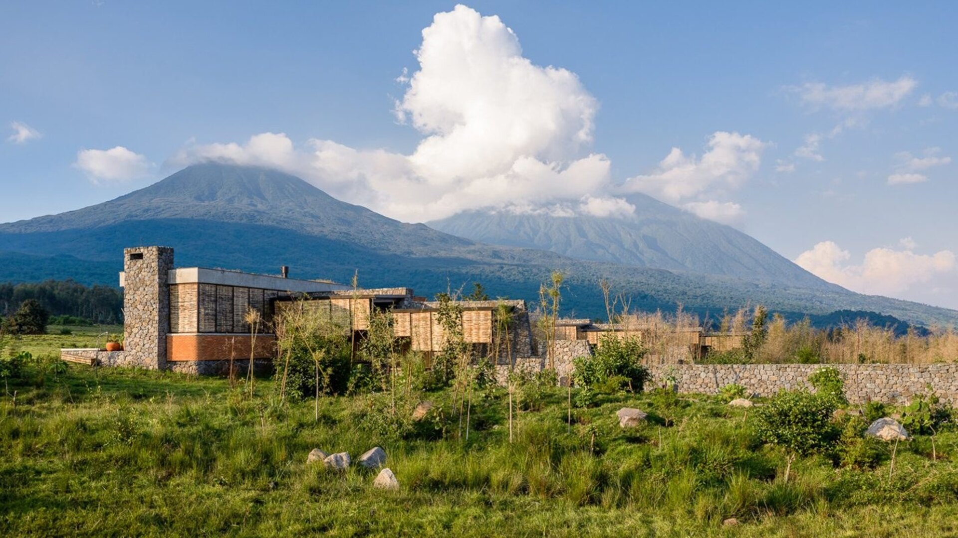 Singita Kwitonda Lodge exterior with volcanic peaks of Volcanoes National Park