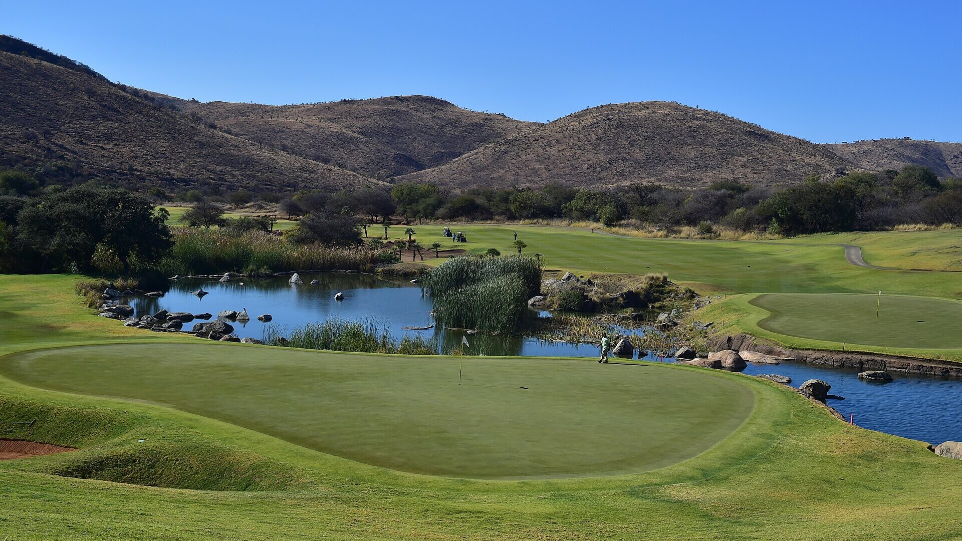 The Gary Player Country Club championship golf course at Sun City with water and bushveld mountains