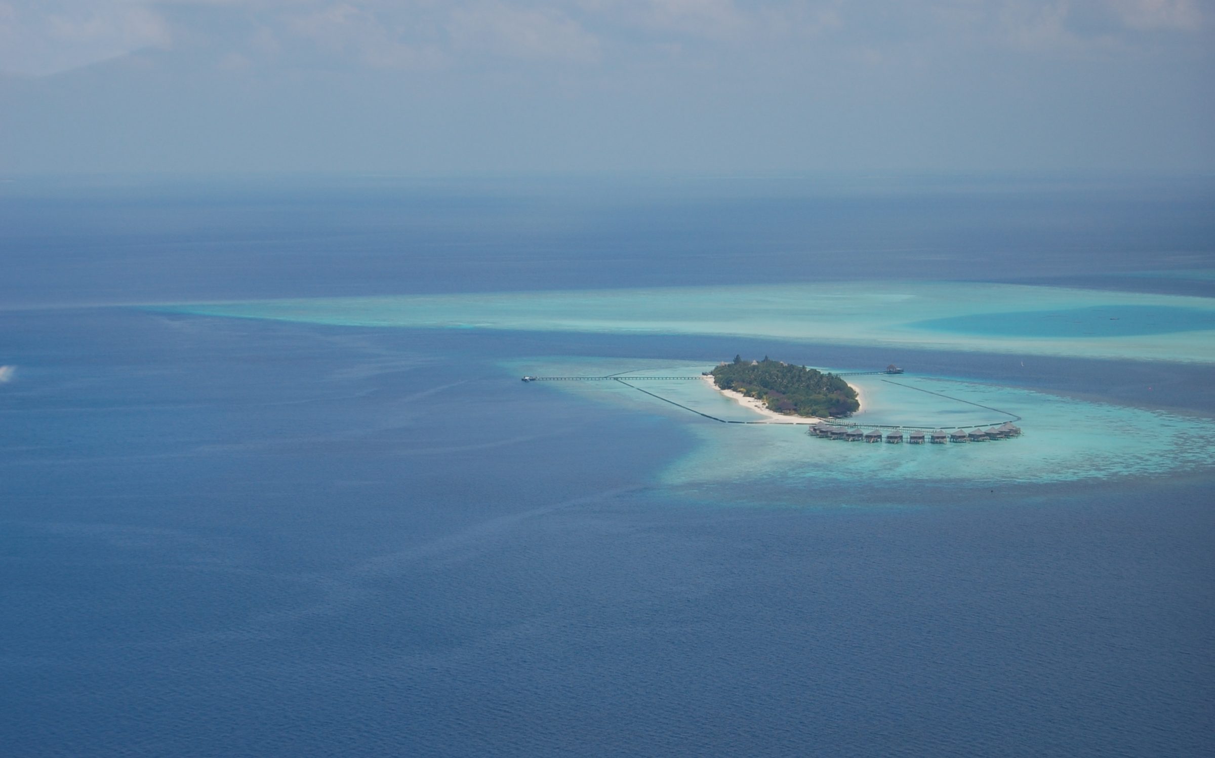 Aerial view of a Maldives island ringed by overwater villas and a turquoise lagoon inside a coral atoll — Top 10 Best Maldives holiday packages 2026 and 2027