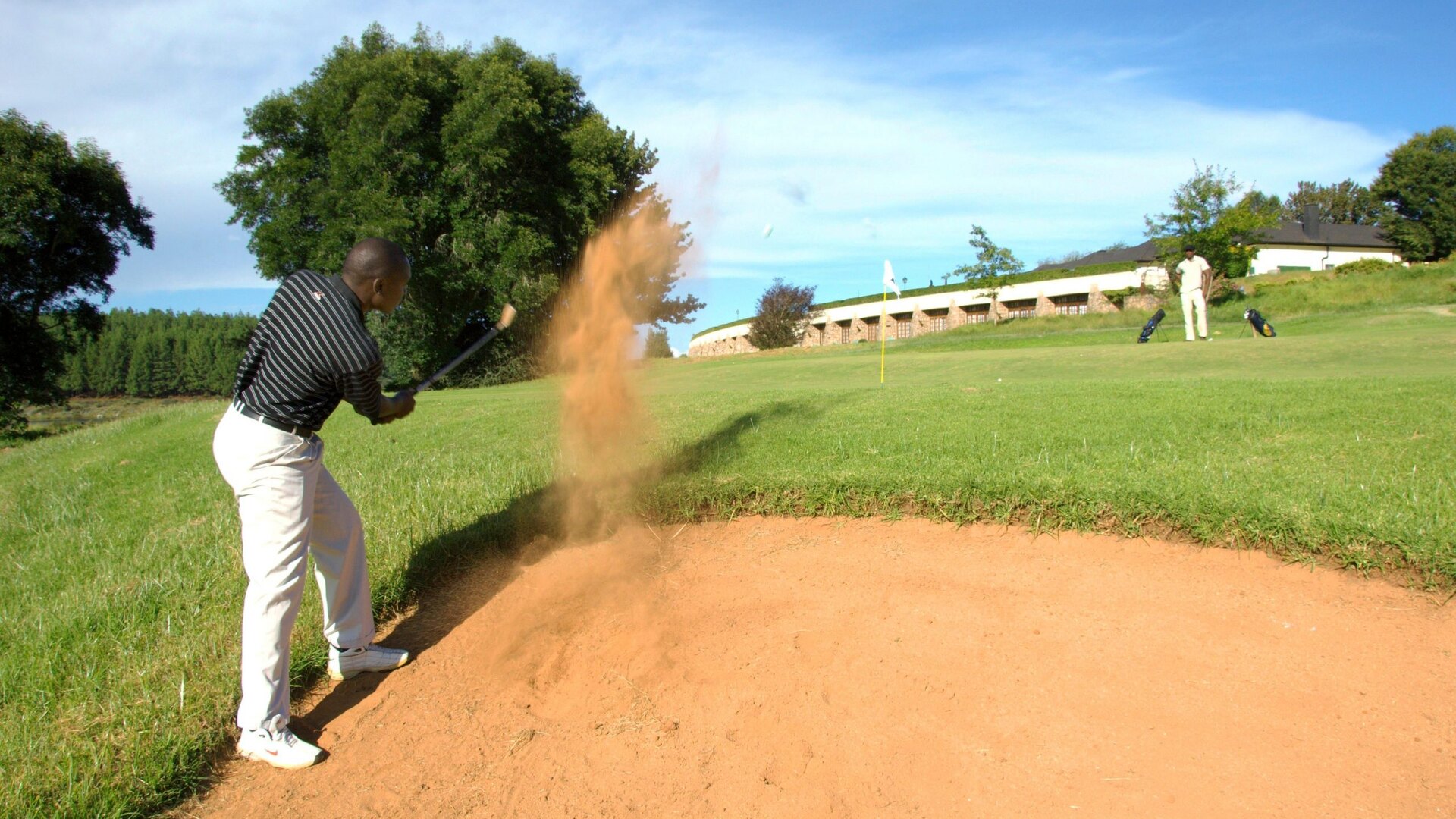 A golfer playing from a bunker at the Gary Player-designed Elephant Hills course above the Zambezi at Victoria Falls