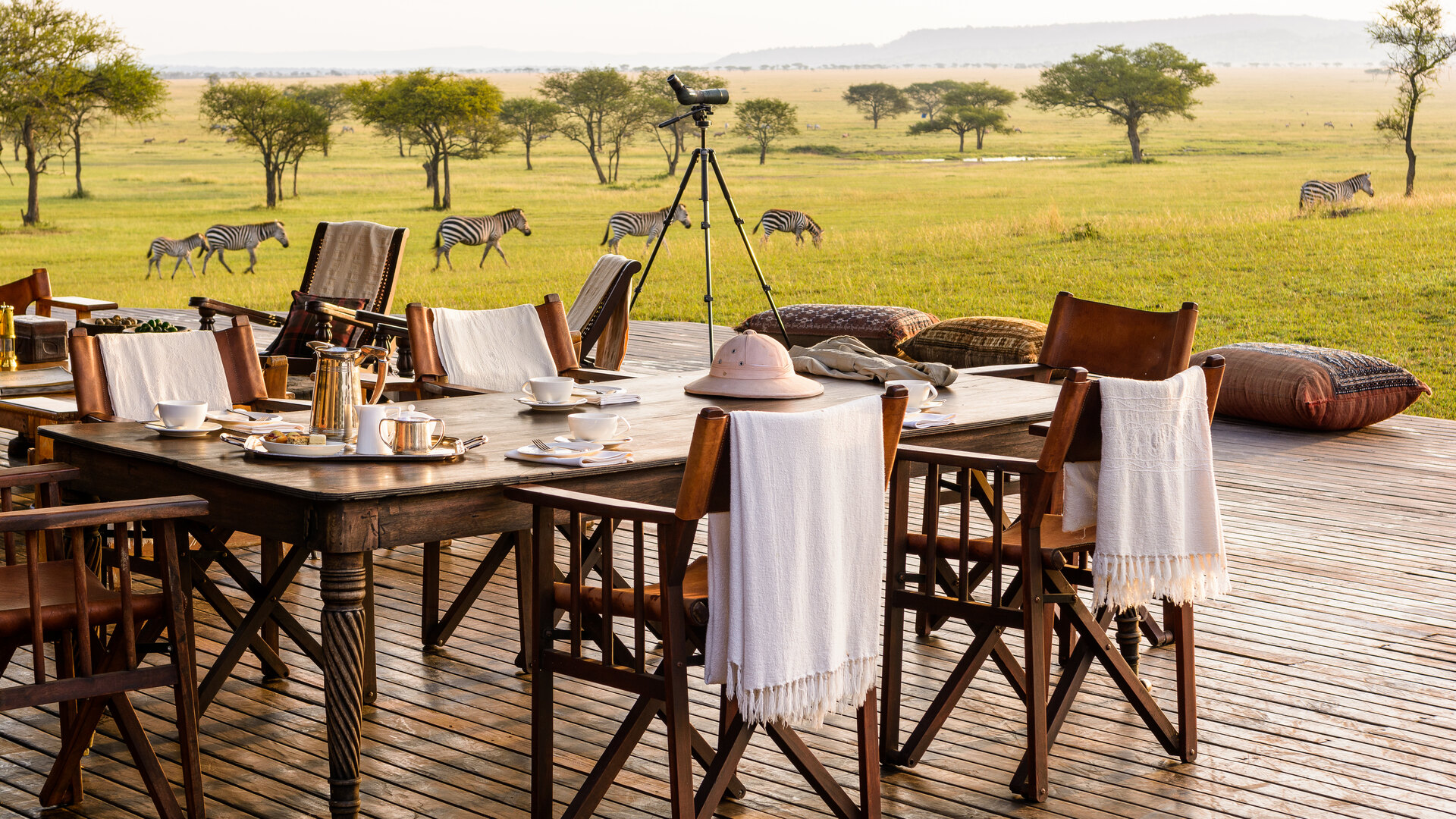 A dining table set for a bush meal on the open plains at golden hour