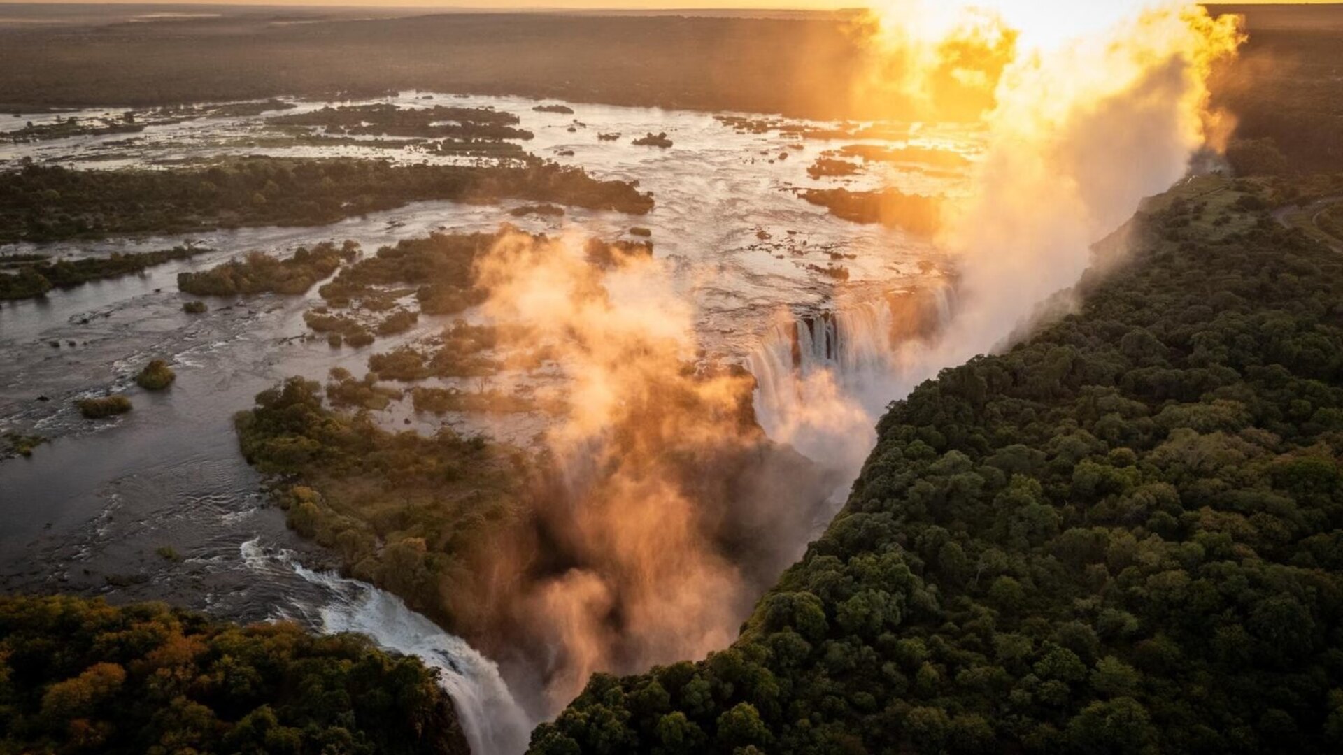 Victoria Falls at sunset with golden light on the rising spray