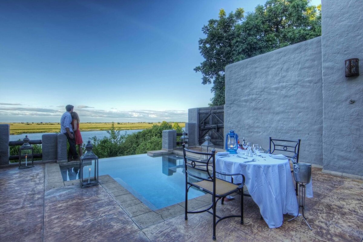 A couple by the infinity pool at Chobe Game Lodge gazing over the Chobe River floodplains