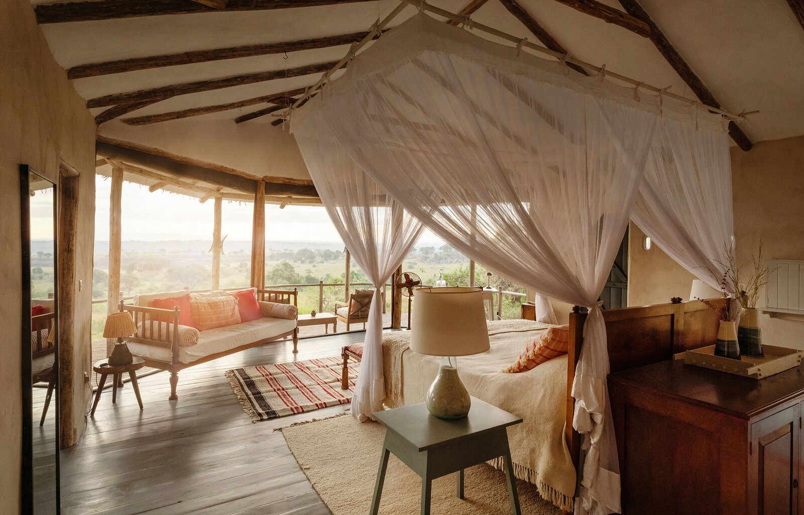 Open-fronted room interior at Lamai Serengeti with a canopy bed framing the Serengeti view