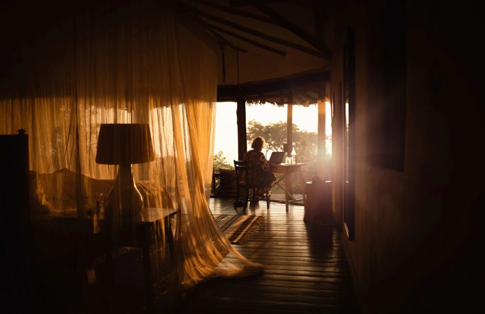 Guest room at Lamai Serengeti in warm early-morning light with billowing drapes