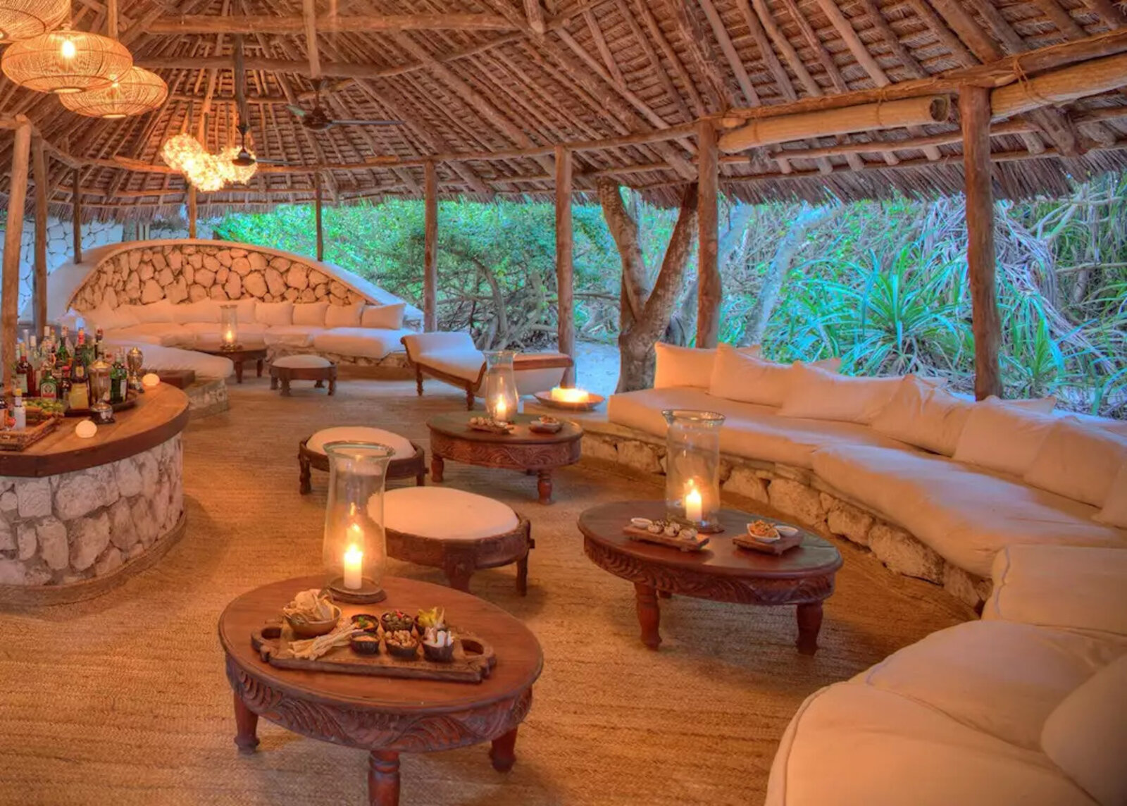 andBeyond Mnemba Island Lodge open makuti-thatch lounge and bar under palms, Zanzibar beach
