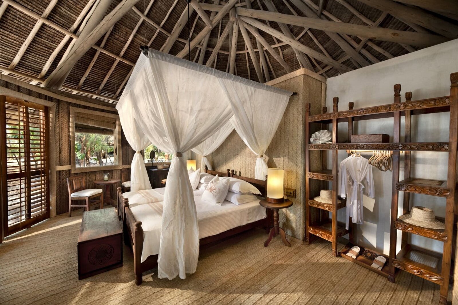 andBeyond Mnemba Island banda bedroom with four-poster net and beach view, Zanzibar honeymoon