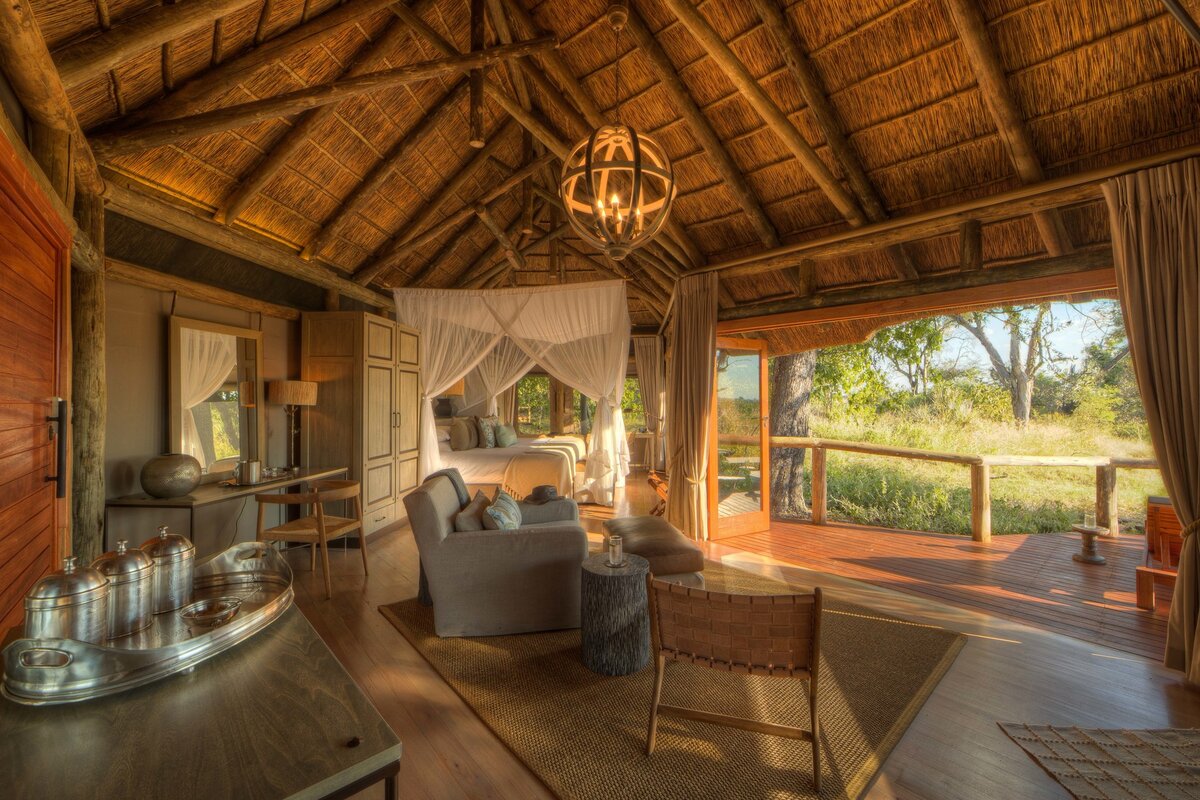 Camp Moremi guest suite interior — four-poster bed and Delta views