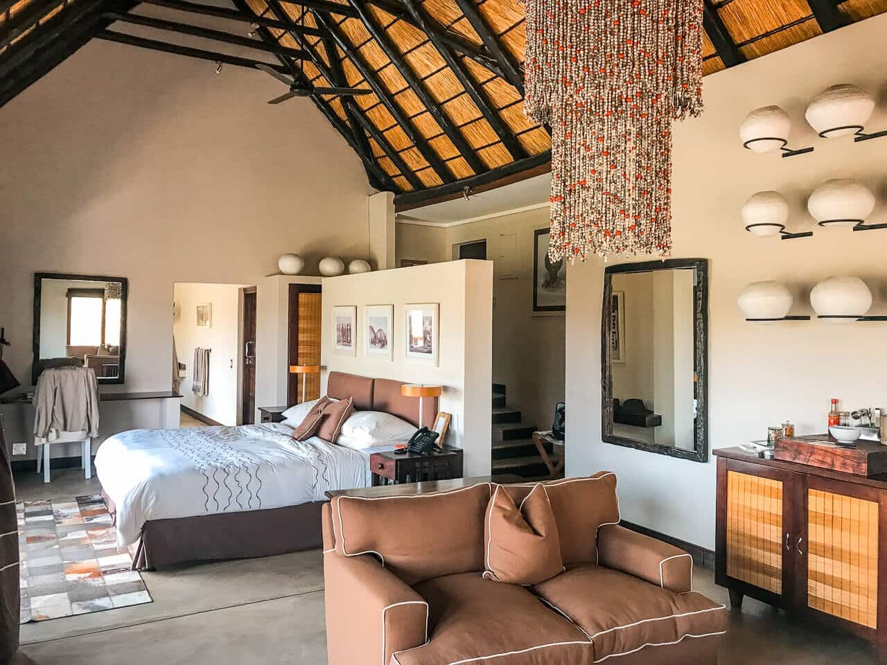 andBeyond Phinda Mountain Lodge suite with bed and lounge under a thatched roof, KwaZulu-Natal