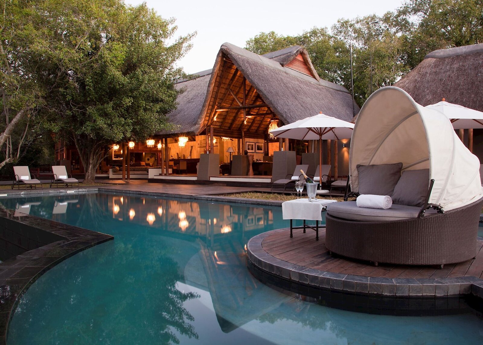 Royal Chundu Zambezi River Lodge pool deck and thatched lounge at dusk near Victoria Falls, Zambia