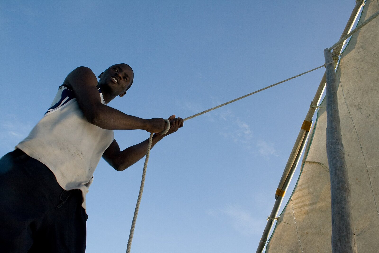 A local crew raising the sail of a traditional dhow on the coast beside Saadani Safari Lodge