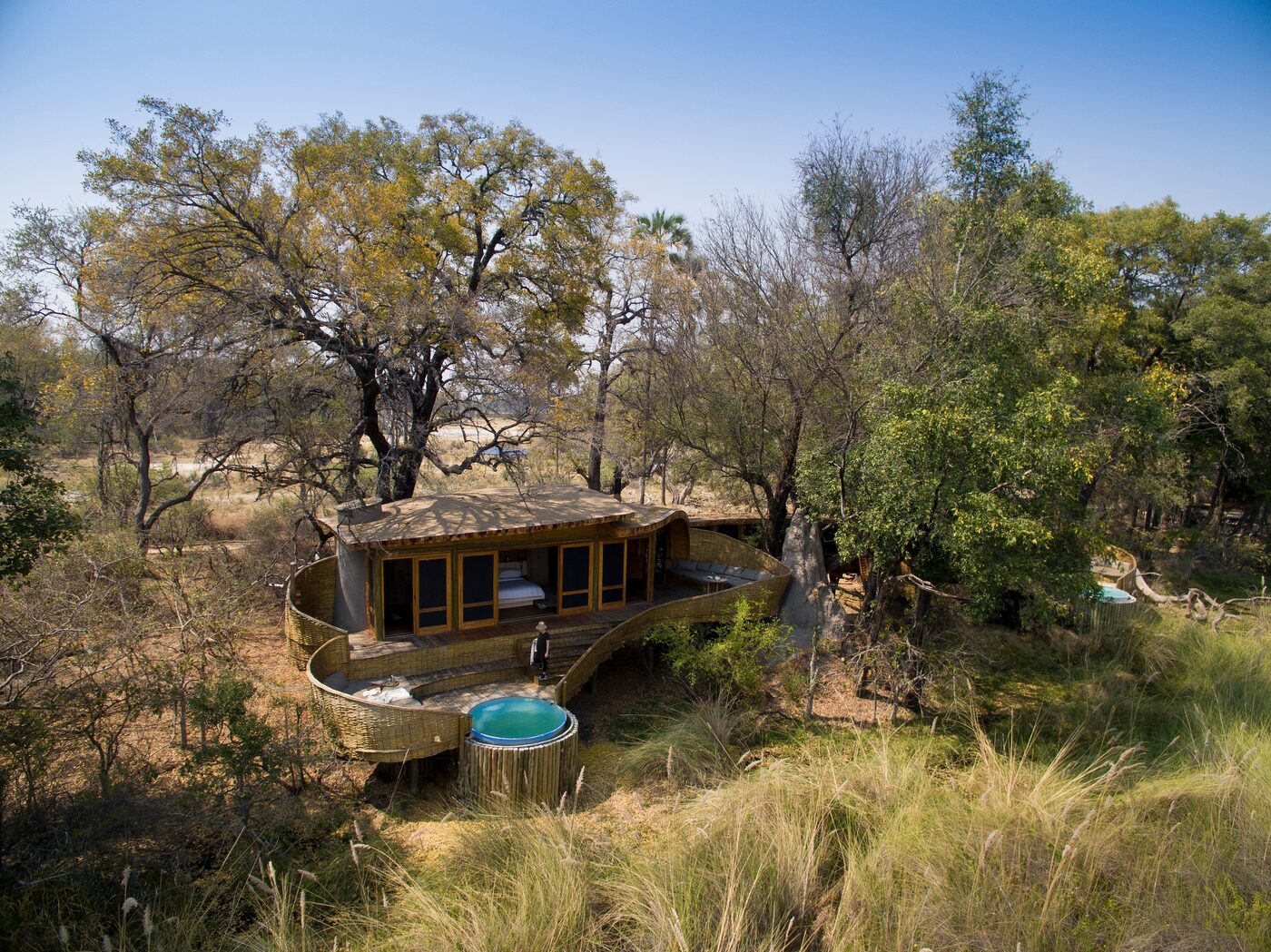 andBeyond Sandibe Okavango Safari Lodge suite exterior on stilts amid delta woodland, Botswana