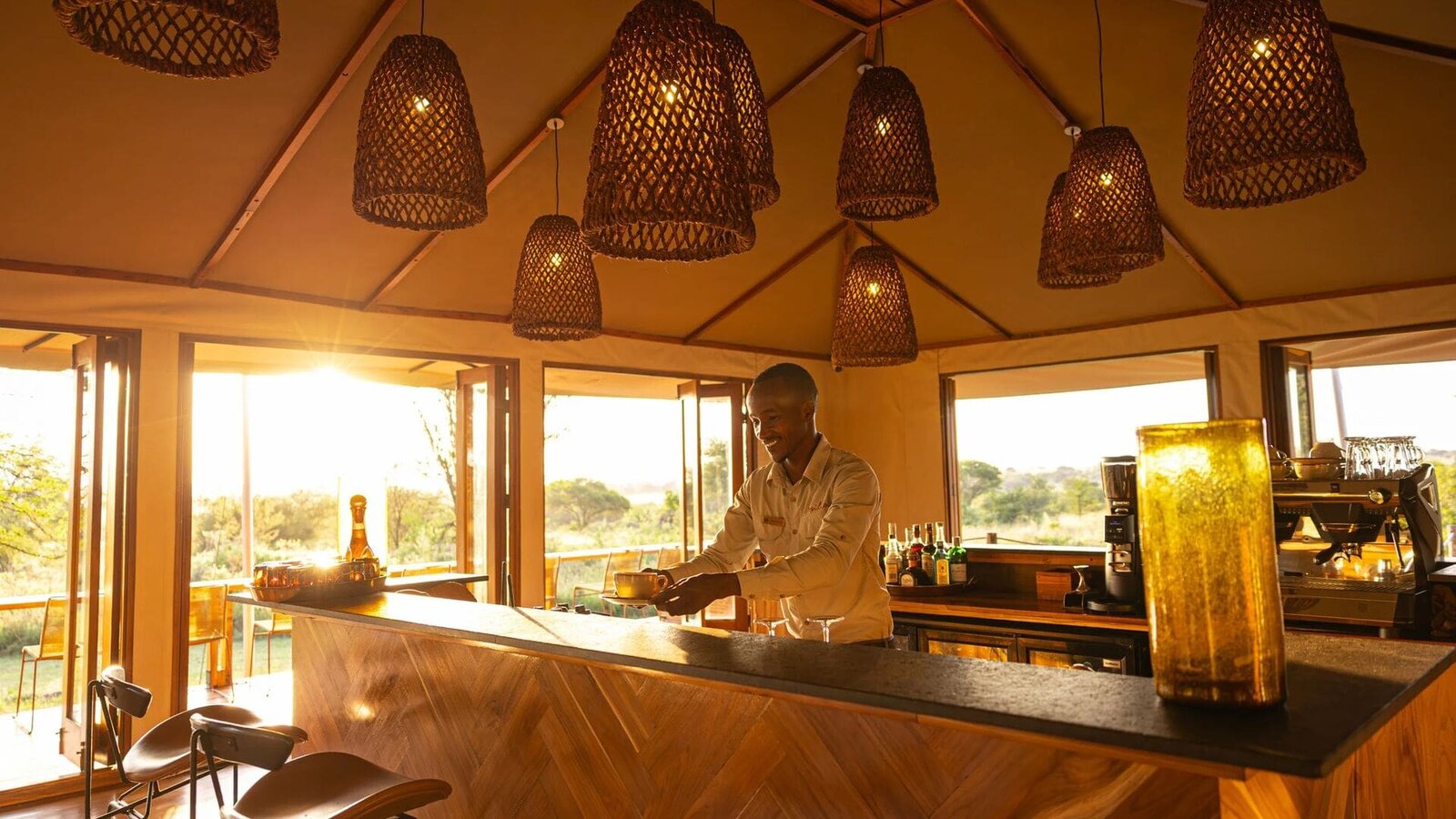 Bar and mess tent at Sayari Camp at sunset with a bartender preparing drinks