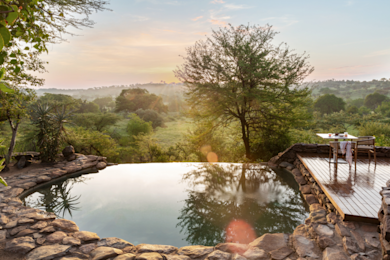 Sundowners at the rim-flow infinity pool as elephants gather at the waterhole below.