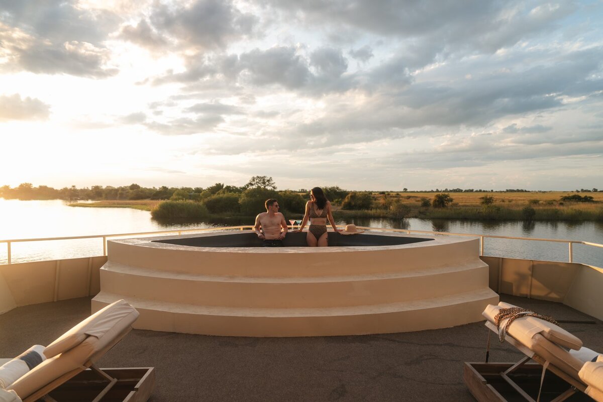 Guests relaxing in the sunset plunge pool on the top deck of the Zambezi Queen houseboat on the Chobe River