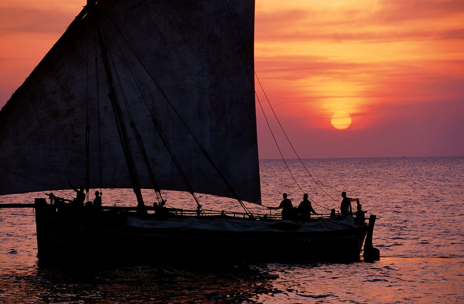 A traditional dhow sailing against a golden sunset off Zanzibar