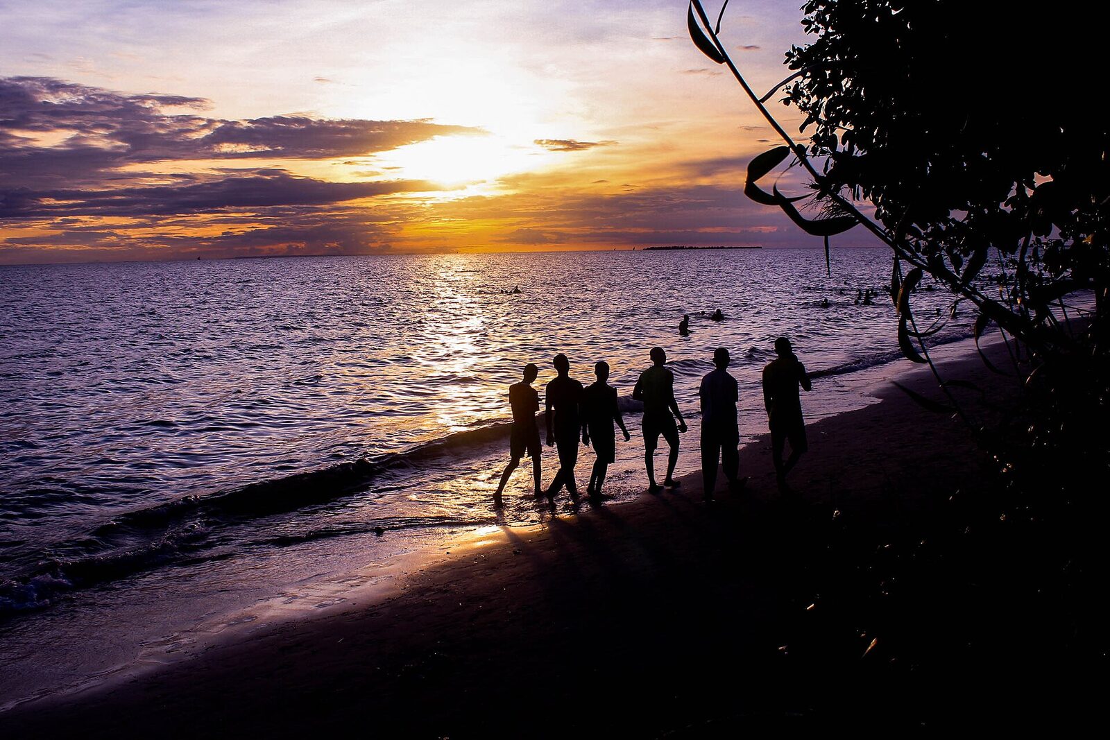 People walking along a Zanzibar beach at sunset